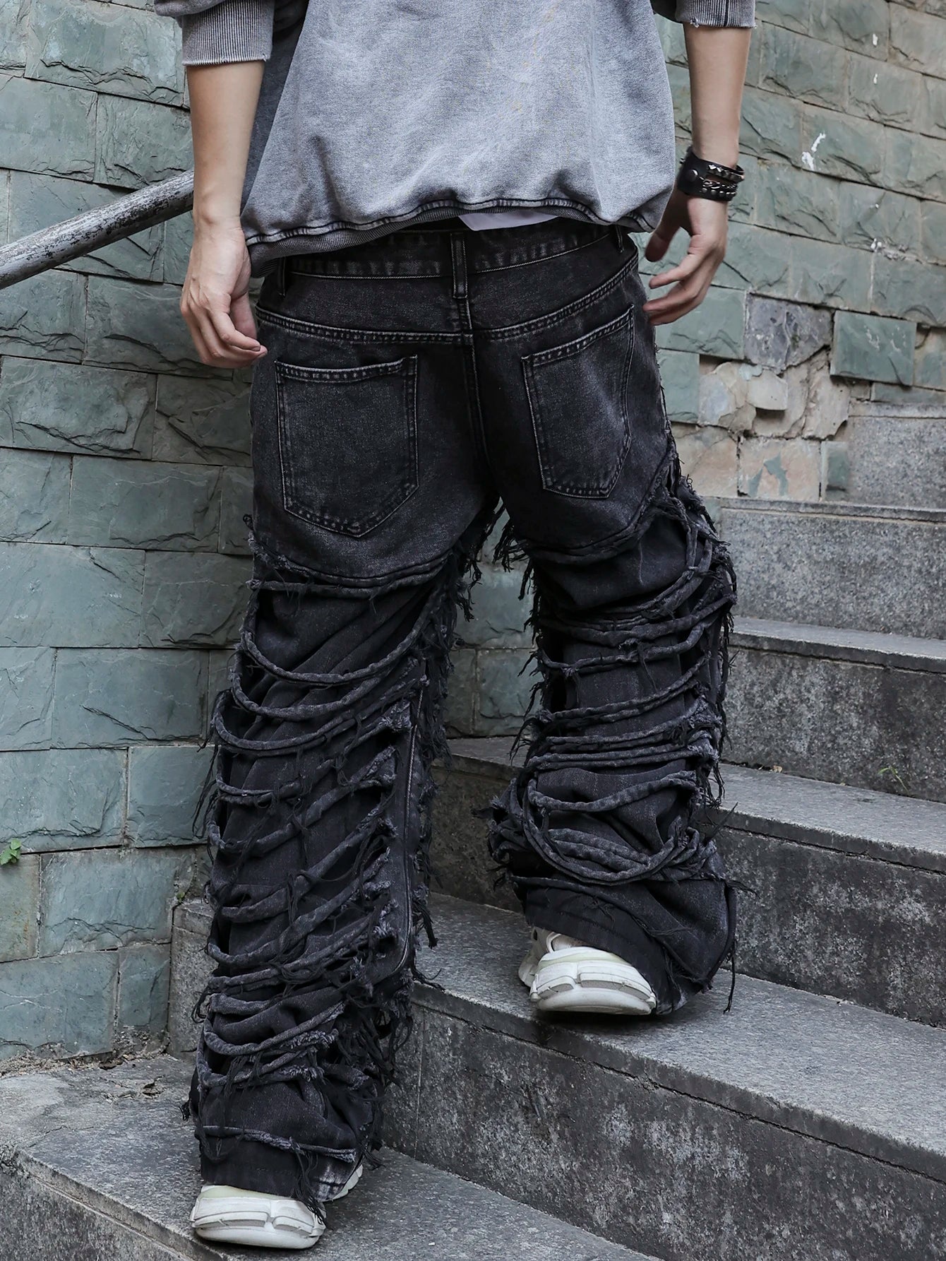 Men's black jeans. With a design of (ripped holes) and tassels. In a street trend style.